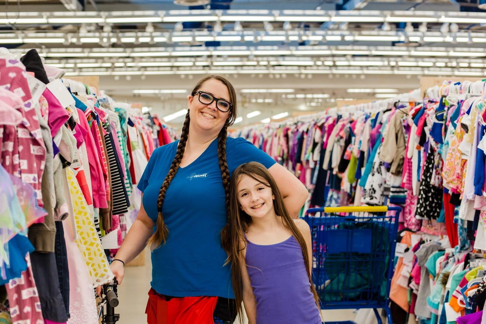 mom and daughter standing together in an aisle of clothes